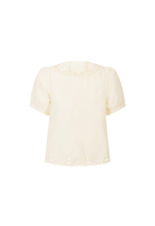 A cream-colored short-sleeve blouse with eyelet lace trim at the collar and hem, displayed against a solid white background.