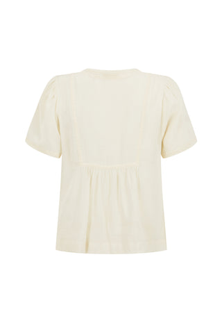 A woman wearing a loose white short-sleeve tie-front blouse and brown shorts