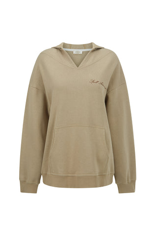 A woman outdoors wearing a beige pullover hoodie with a kangaroo pocket