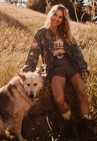 A woman sitting in a grassy field with a dog