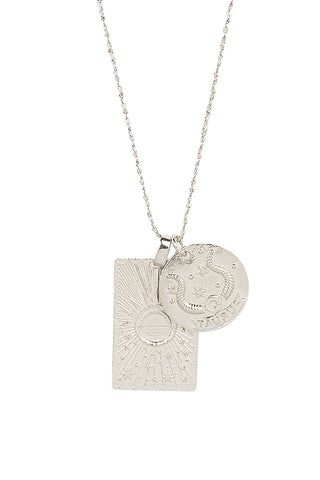 close-up-front-view-of-spell-s-taurus-stargazer-zodiac-necklace-charms-one-charm-is-of-a-rectangular-shape-and-features-a-sun-with-stars-while-the-other-charm-is-circular-and-features-the-zodiac-label-and-icon